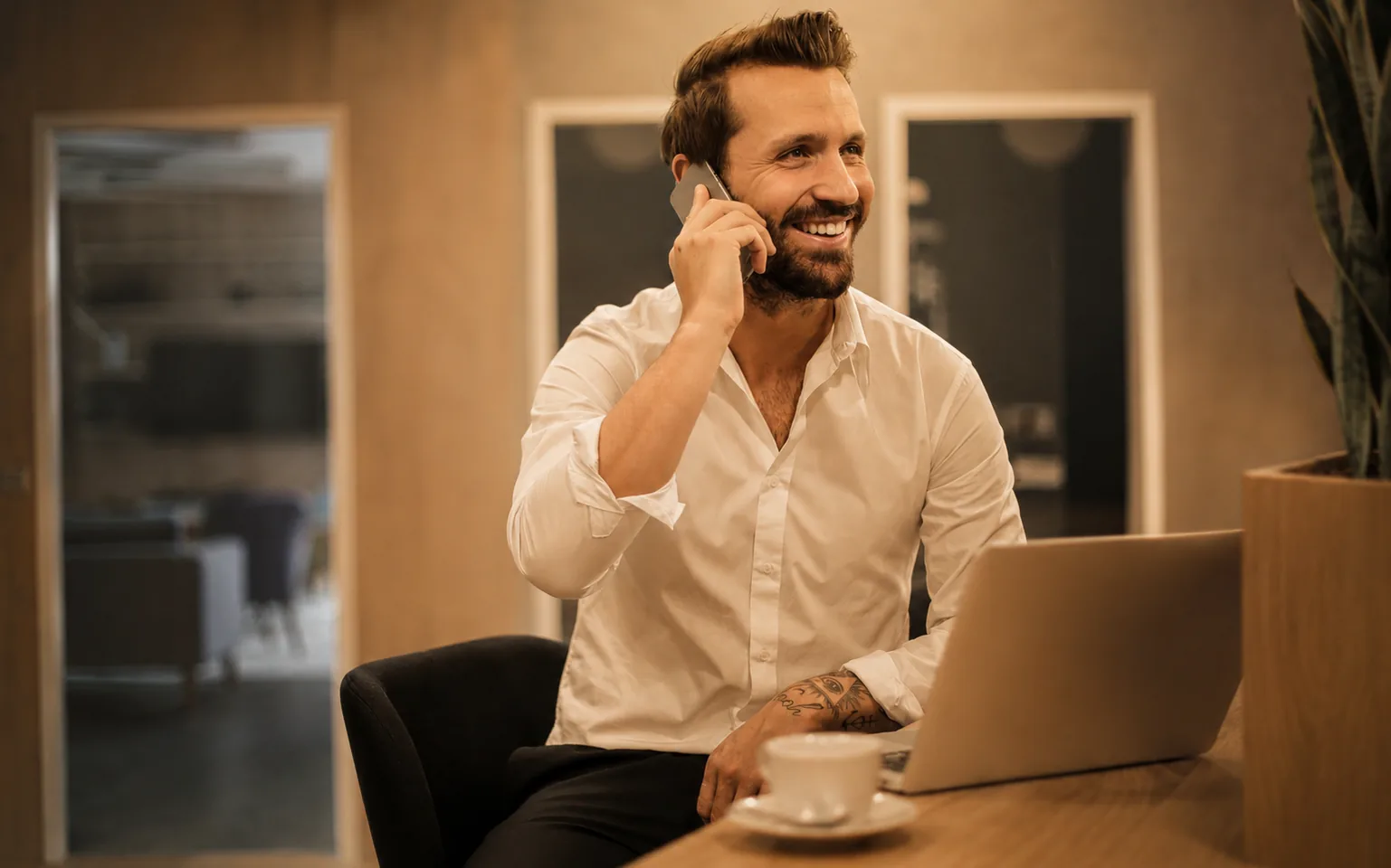 Professional on a phone call at a laptop, coordinating international hiring